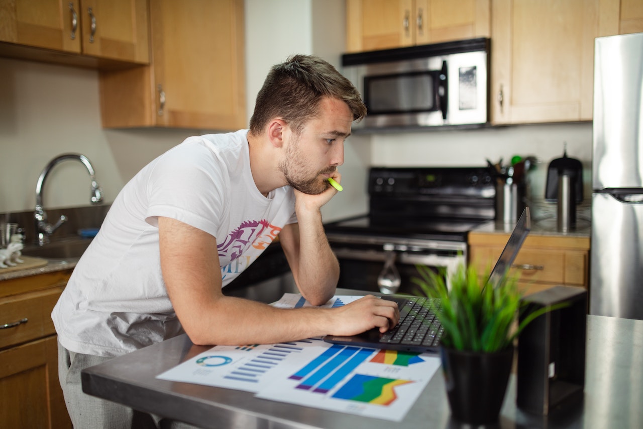 a man standing in front of a computer in kitchen