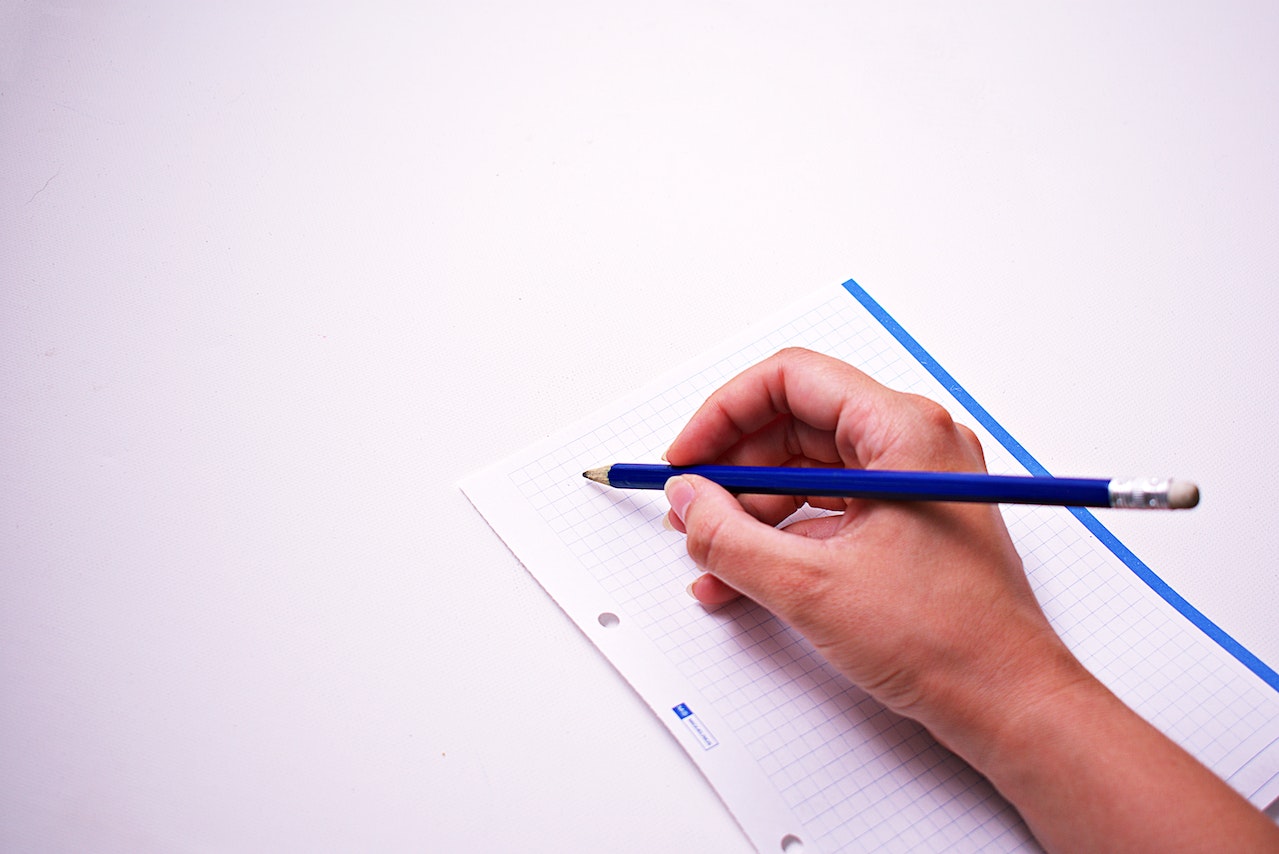 a hand holding a pencil over a sheet of paper